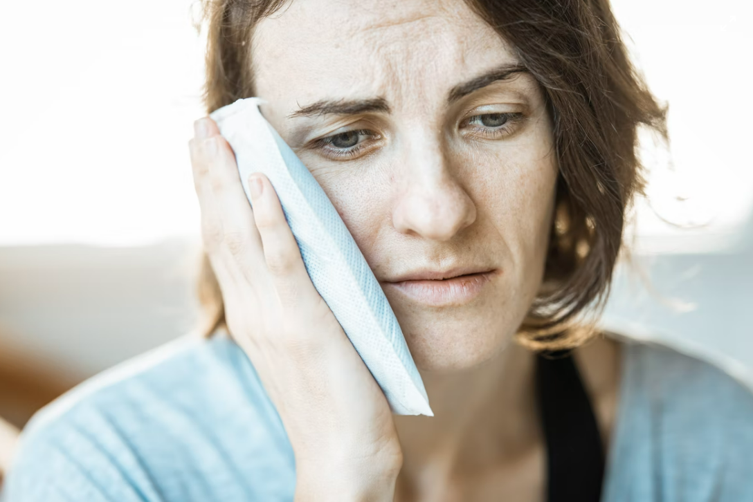 Woman holding an ice pack to her face because of TMJ pain